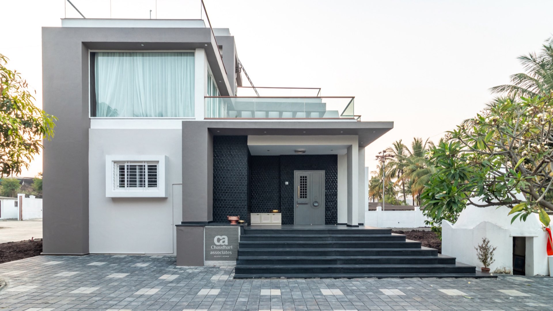 White-and-charcoal contemporary farmhouse façade with a wide stone stair — Ramkrushnahari, Karandi