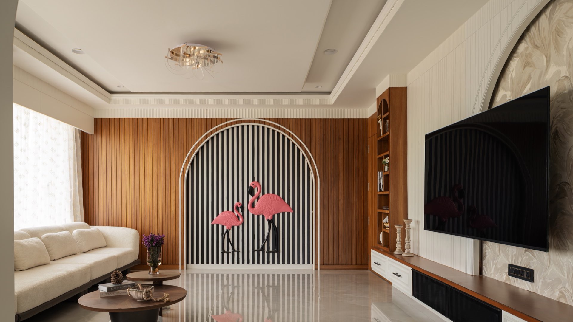 Living room with a striped arch and pink flamingo sculpture against a timber-slatted wall — The Flamingo, Shirur